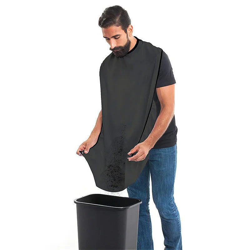 Man wearing a black apron over a black t-shirt, standing next to a black trash can on a white background.
