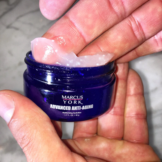 Hand holding a jar of Marcus York Advanced Anti-Aging cream.