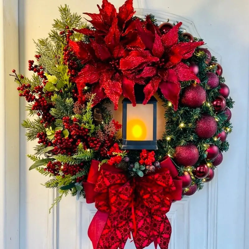 Decorative Christmas wreath with red poinsettias, berries, and a candle on a white door.