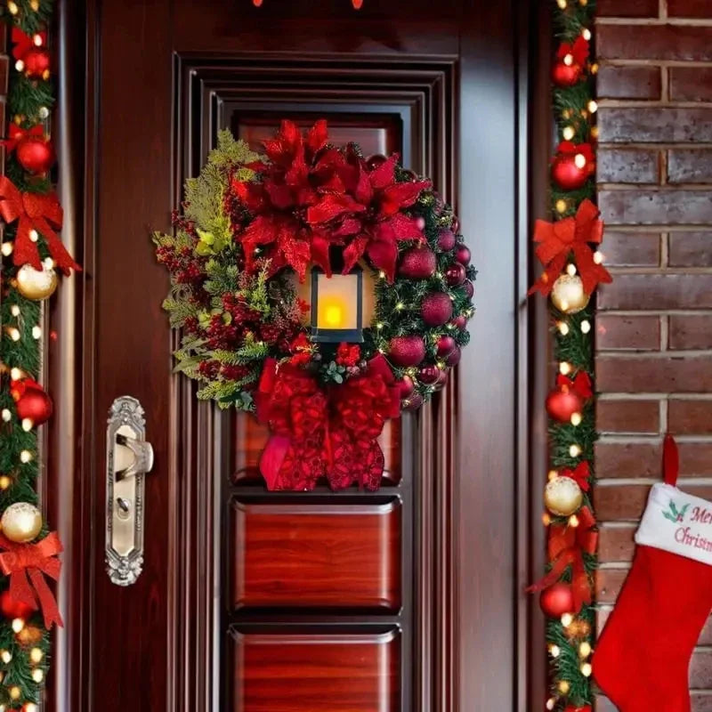Decorative Christmas wreath with red poinsettias and lights on a door with a stocking hanging to the side.