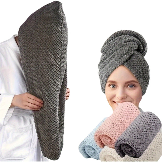 Gray textured towel held by a person and wrapped around a woman's head with additional towels in the background.
