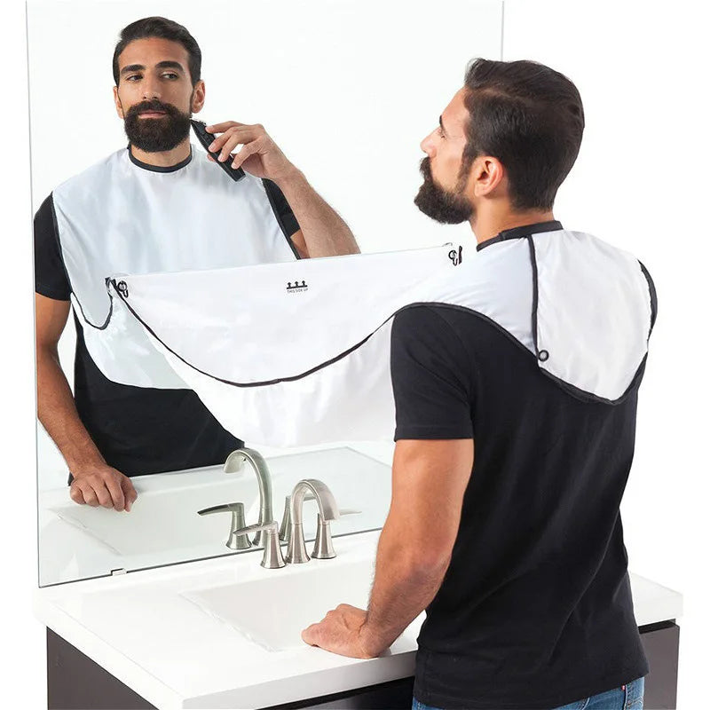 Man using a beard trimmer with a white bib in a bathroom setting