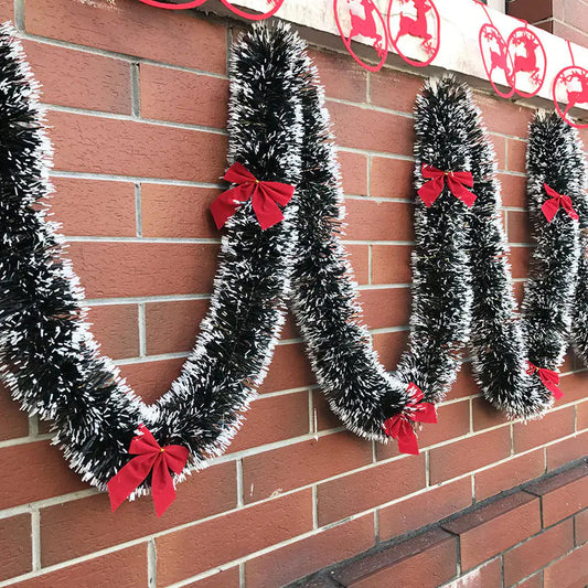 Decorative tinsel letters with red bows on a brick wall
