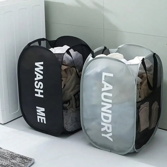 Two laundry bags labeled 'WASH ME' and 'LAUNDRY' on a white surface.
