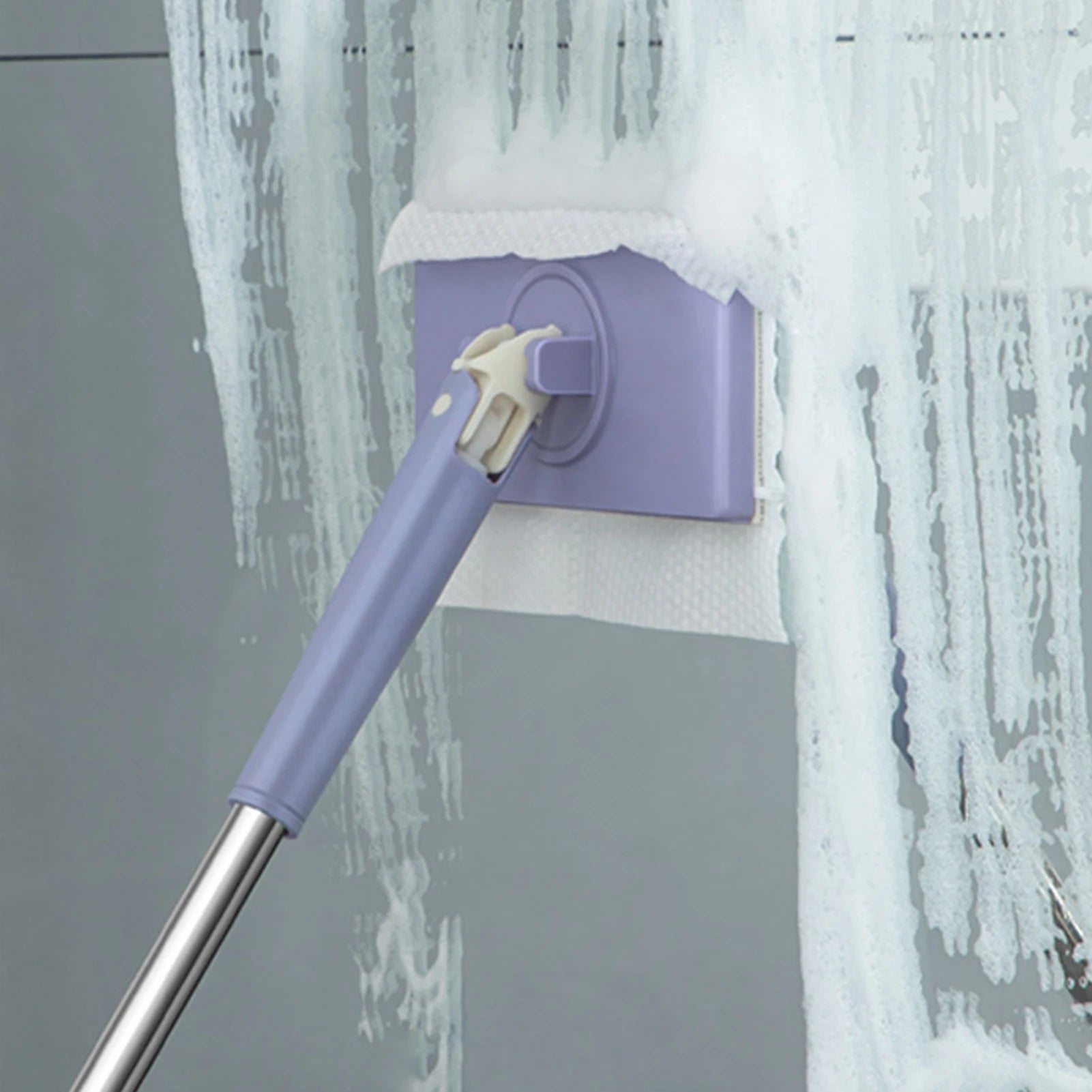 Purple cleaning tool with a spray head against a gray wall with water splashes.