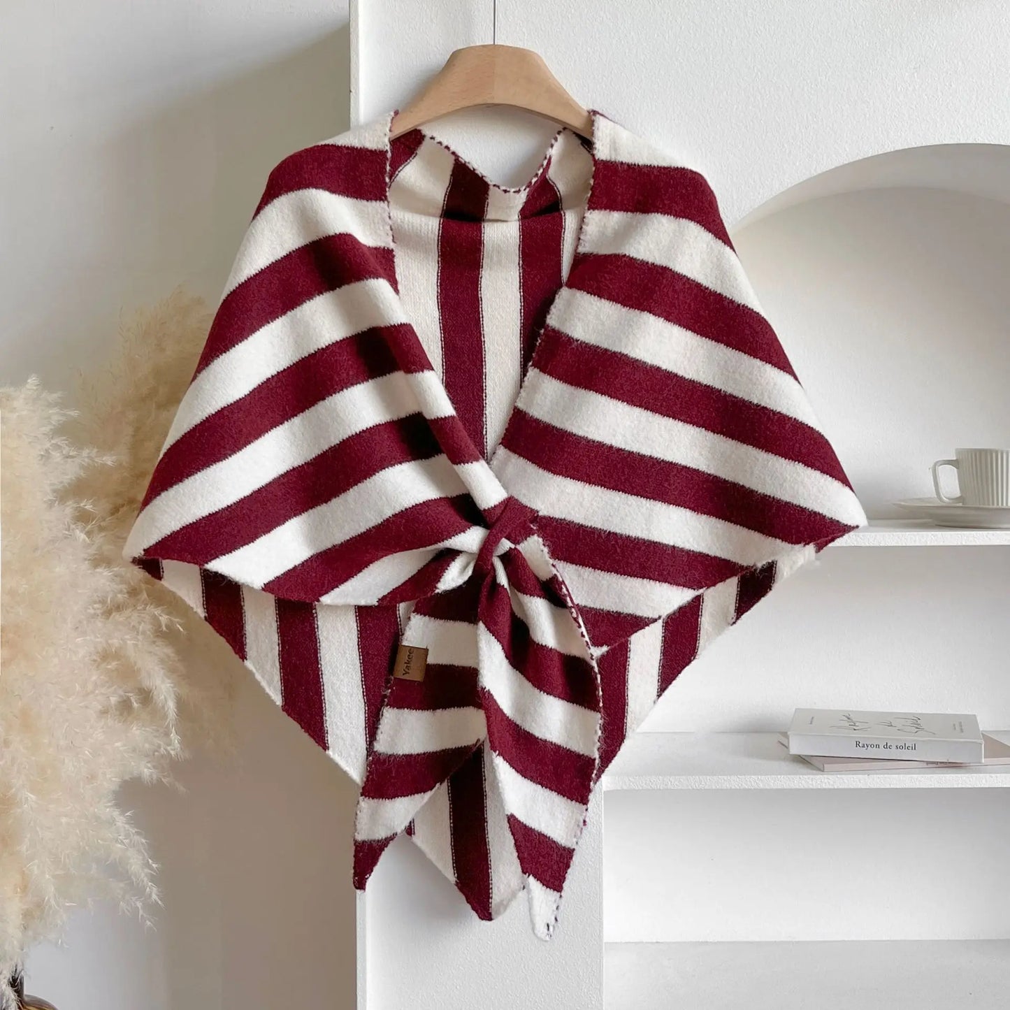 Red and white striped poncho on a wooden hanger against a white background