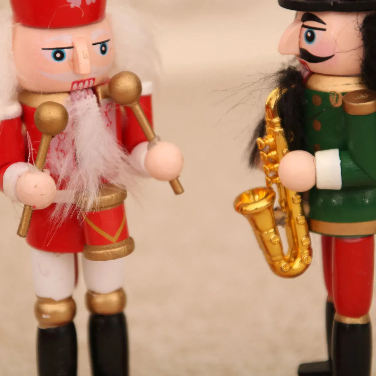 Two nutcracker figurines, one in red with drumsticks and the other in green with a saxophone, on a beige background.