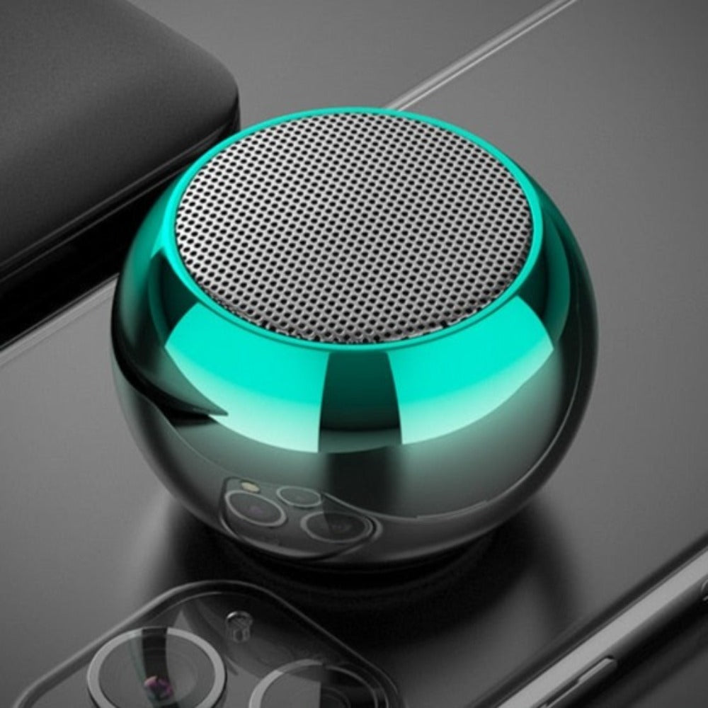 Turquoise portable speaker on a reflective surface