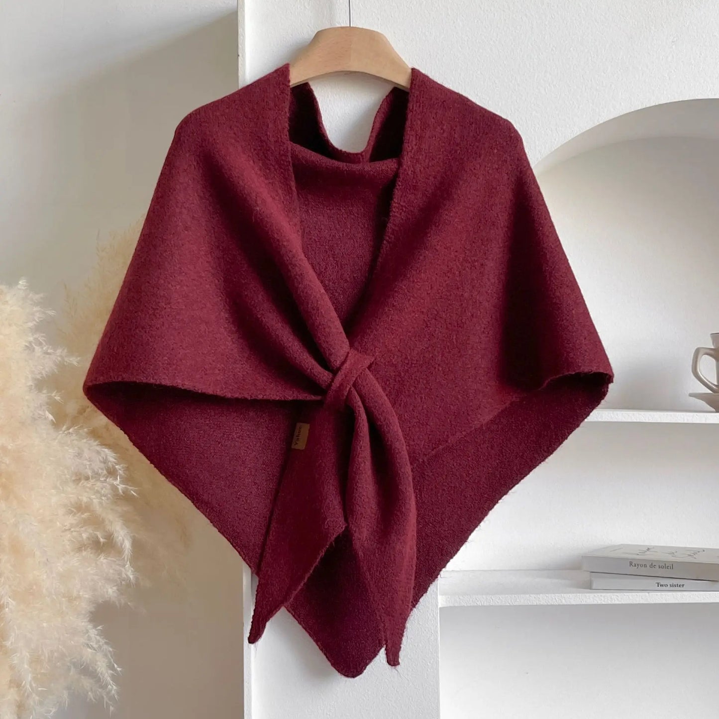 Maroon poncho on a wooden hanger against a neutral background