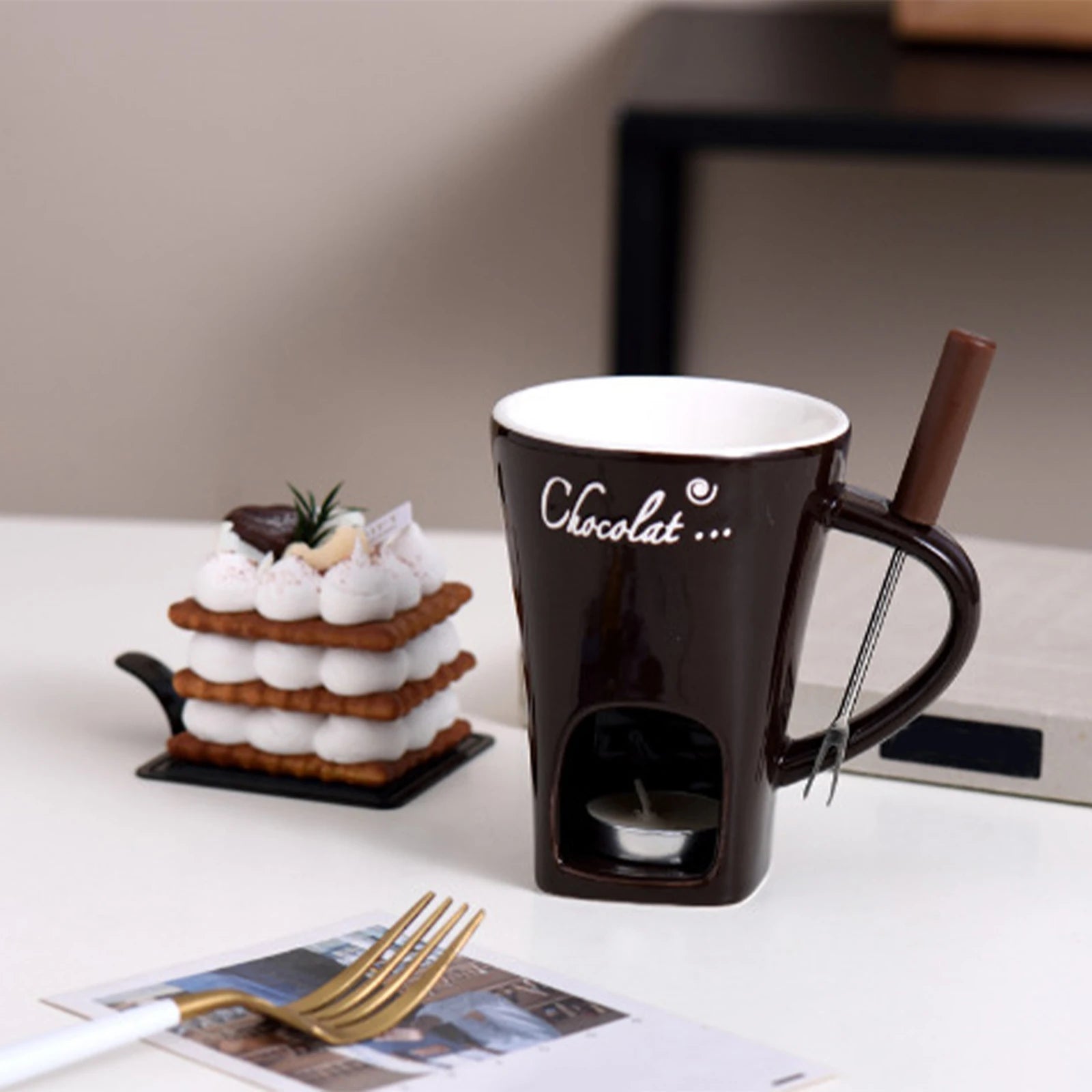 Chocolate-themed mug with a small cake and chocolate bar on a table.