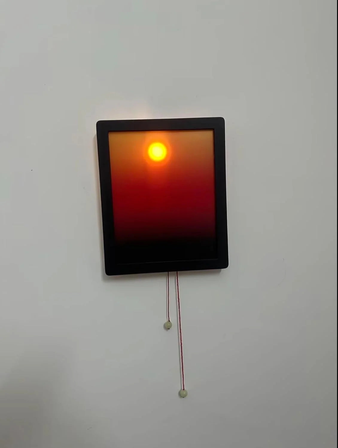 Rectangular digital display with a red and orange gradient on a white wall