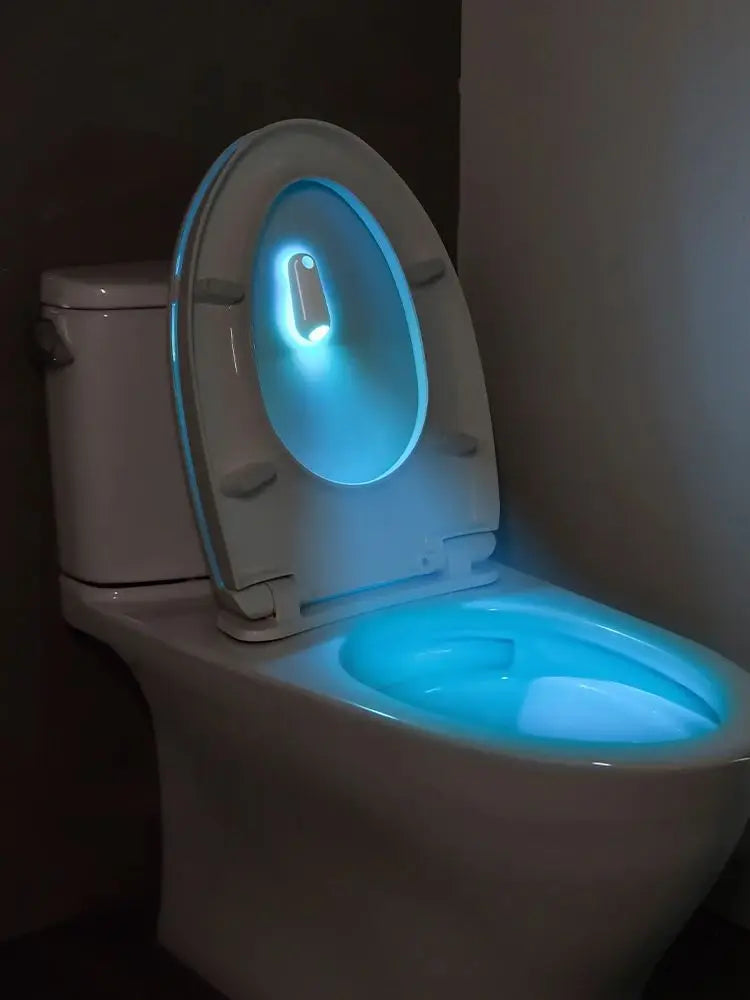 Toilet with a glowing seat and bowl in a dark room