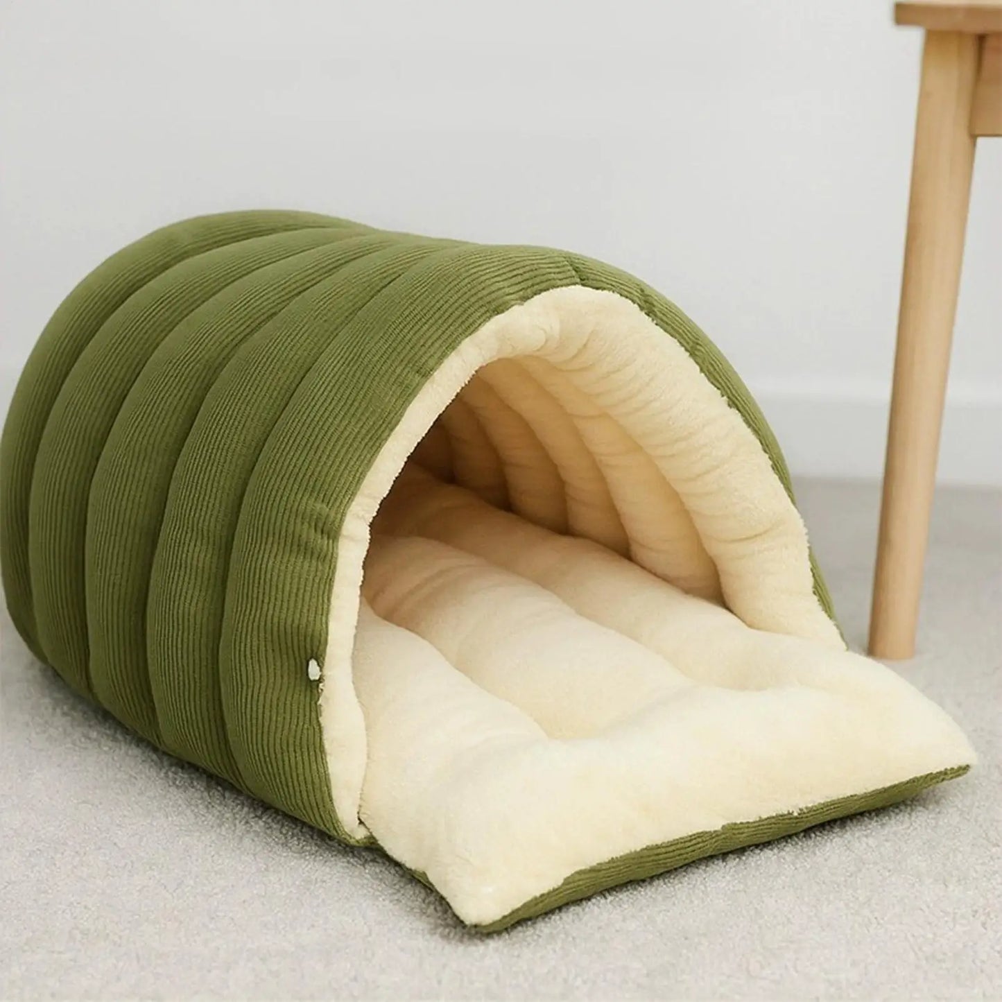 Green pet bed with beige interior on a light gray floor.
