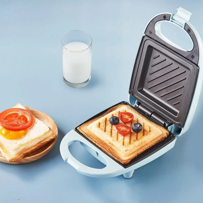 Sandwich maker with a grilled sandwich inside, next to a glass of milk on a blue background