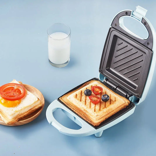 Sandwich maker with a grilled sandwich inside, next to a glass of milk on a blue background