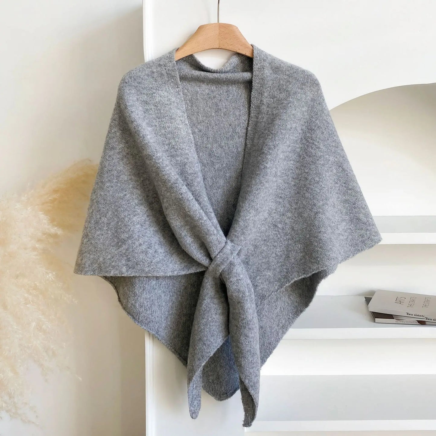 Gray shawl draped over a wooden hanger against a white background