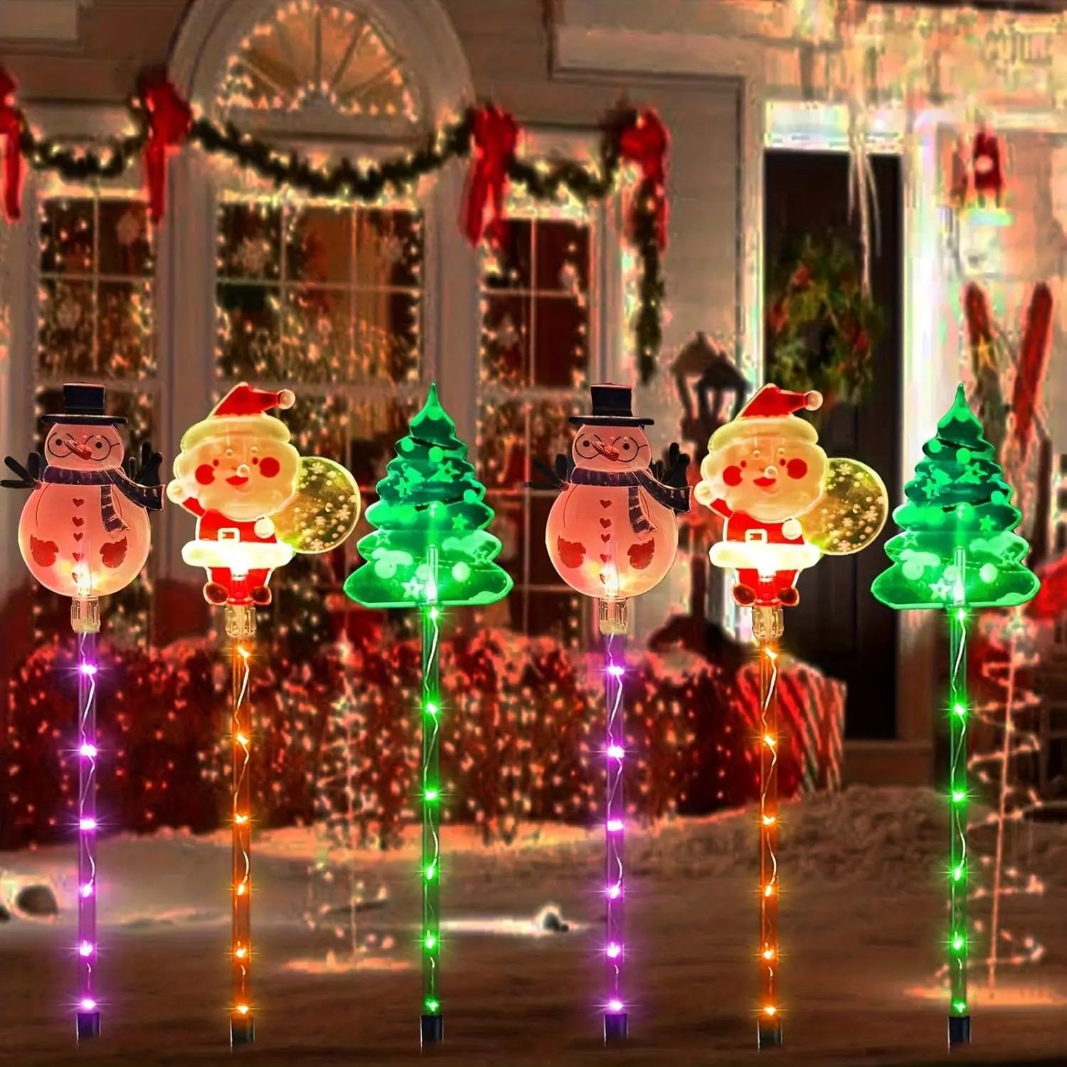 Decorative Christmas lights shaped like Santa Claus, snowmen, and trees in front of a house with holiday decorations.