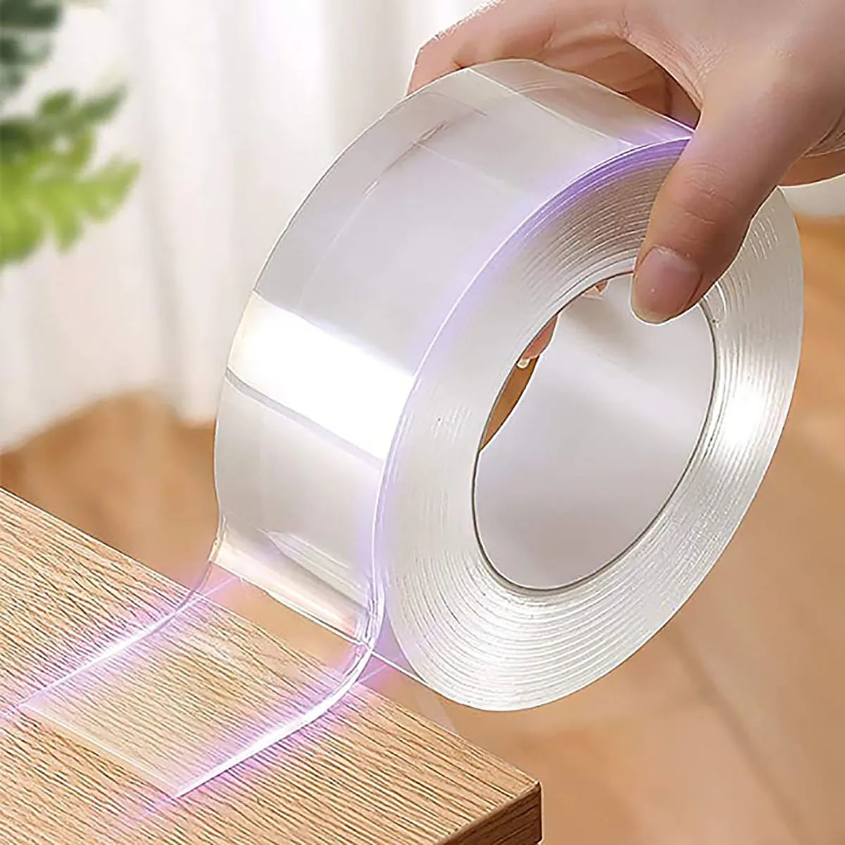 Roll of clear tape being applied to a wooden surface with a blurred background