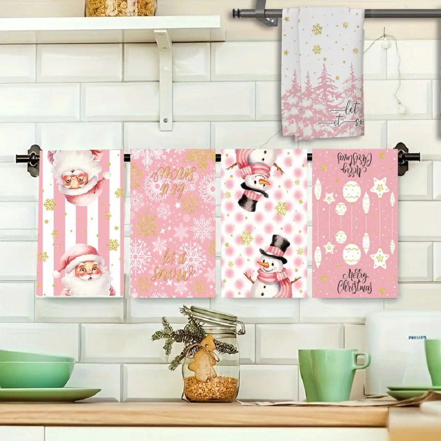 Set of pink Christmas-themed towels hanging on a rack with decorative items on a kitchen counter.