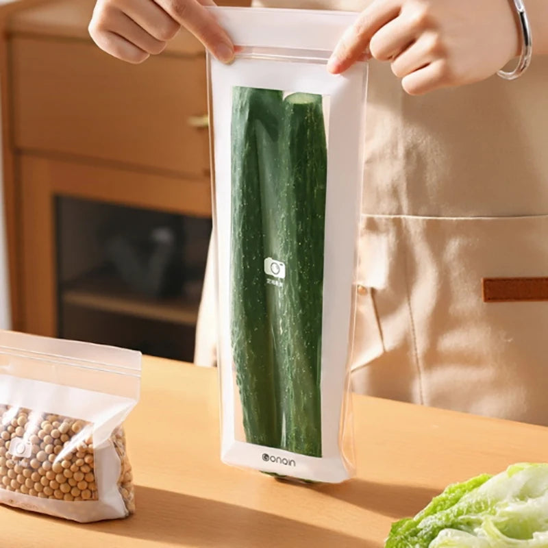 Person holding a vacuum-sealed bag with cucumbers on a kitchen counter.