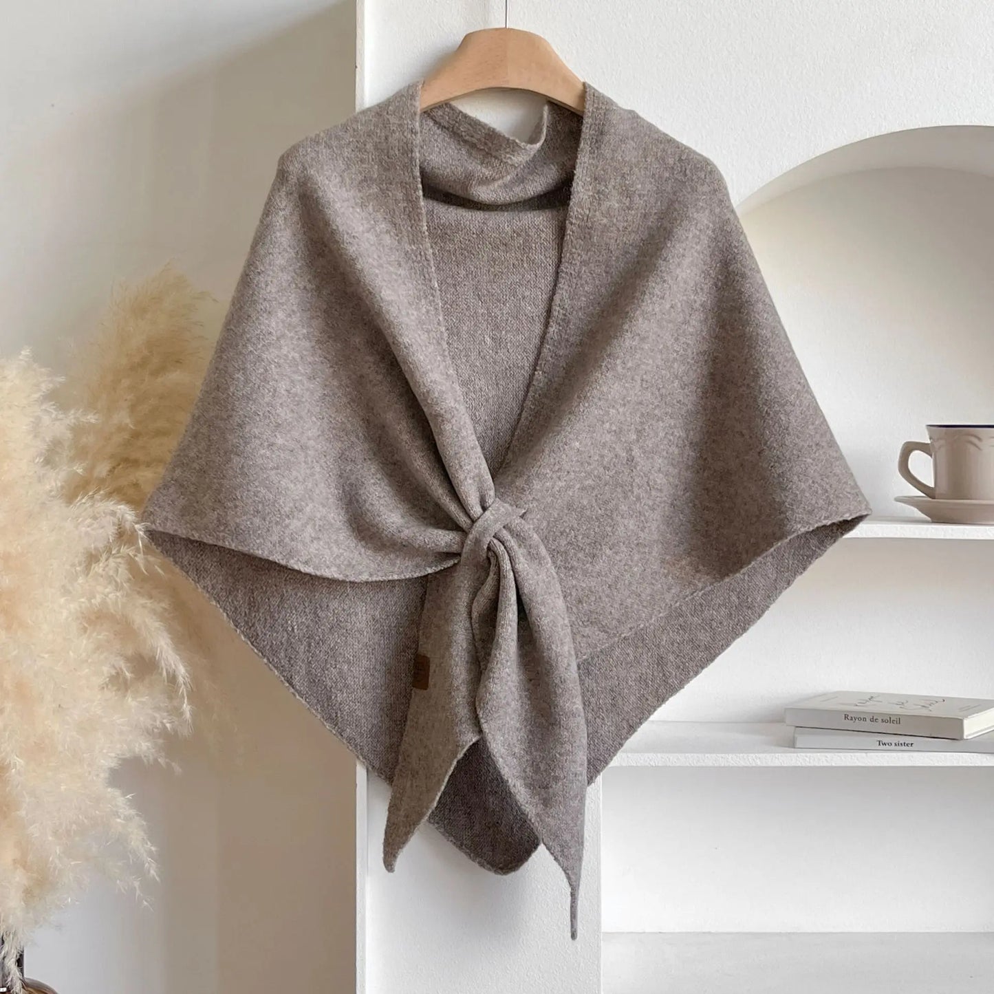 Brown poncho on a hanger against a neutral background