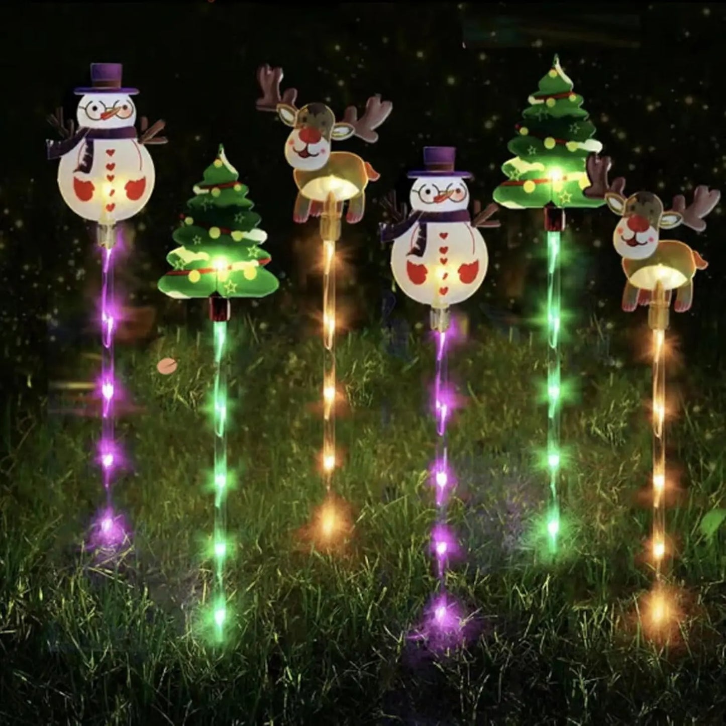 Decorative outdoor lights shaped like Christmas trees, snowmen, and reindeer on grass.