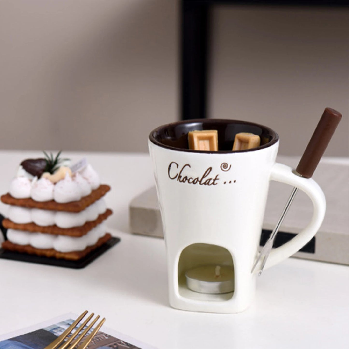 White mug with 'Chocolat' text, chocolate bar, and marshmallows on a blurred background