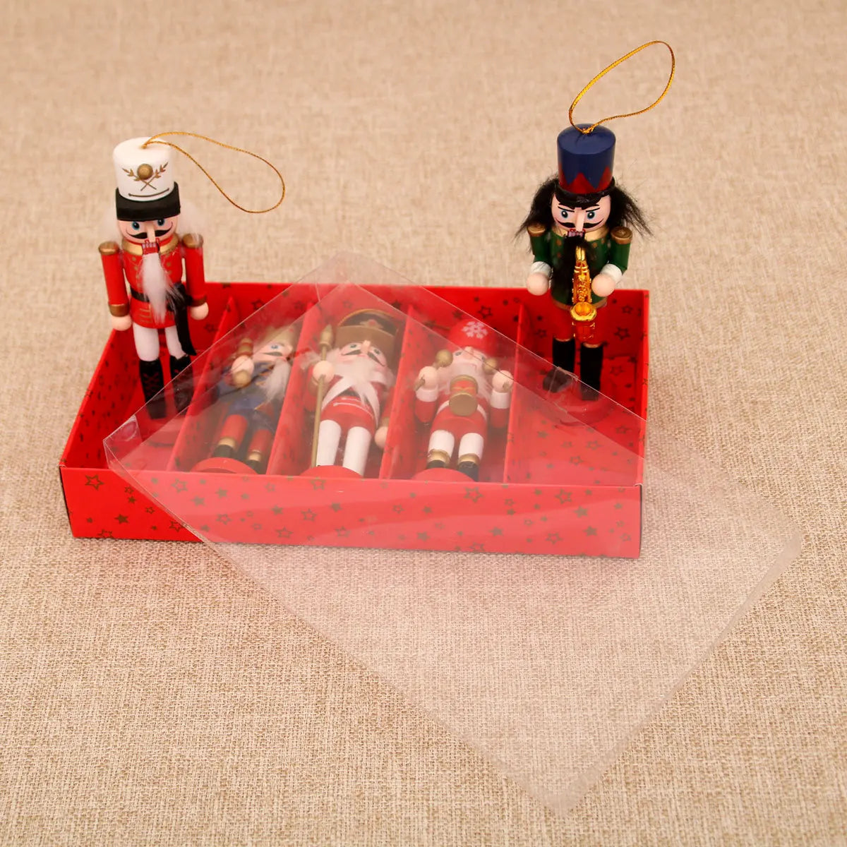 Set of Nutcracker ornaments with a clear box on a beige surface
