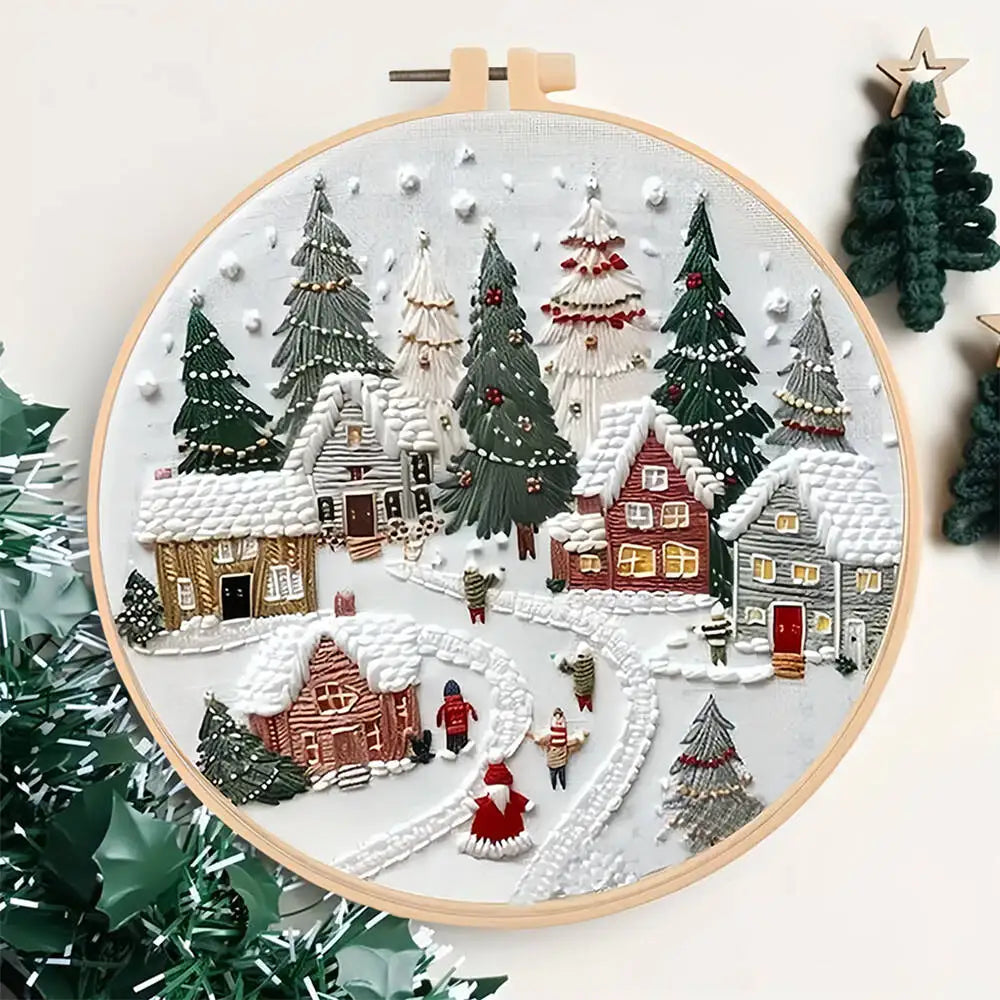 Embroidery hoop with a winter village scene surrounded by Christmas trees.