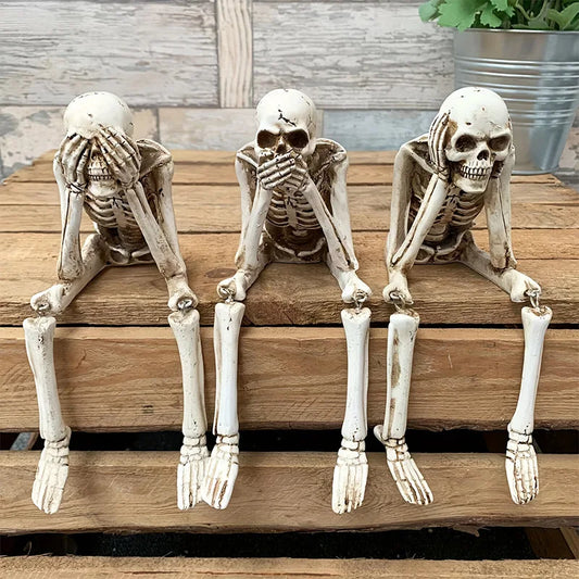 Three skeleton figurines on a wooden surface with a neutral background