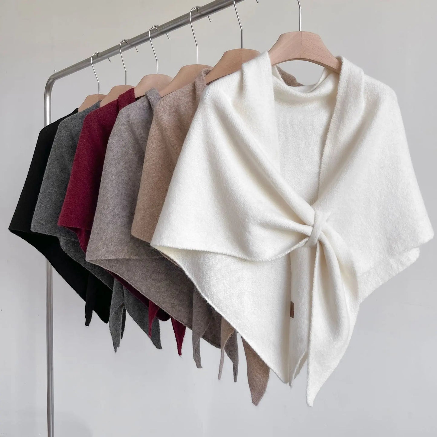 Collection of colorful ponchos on hangers against a white background