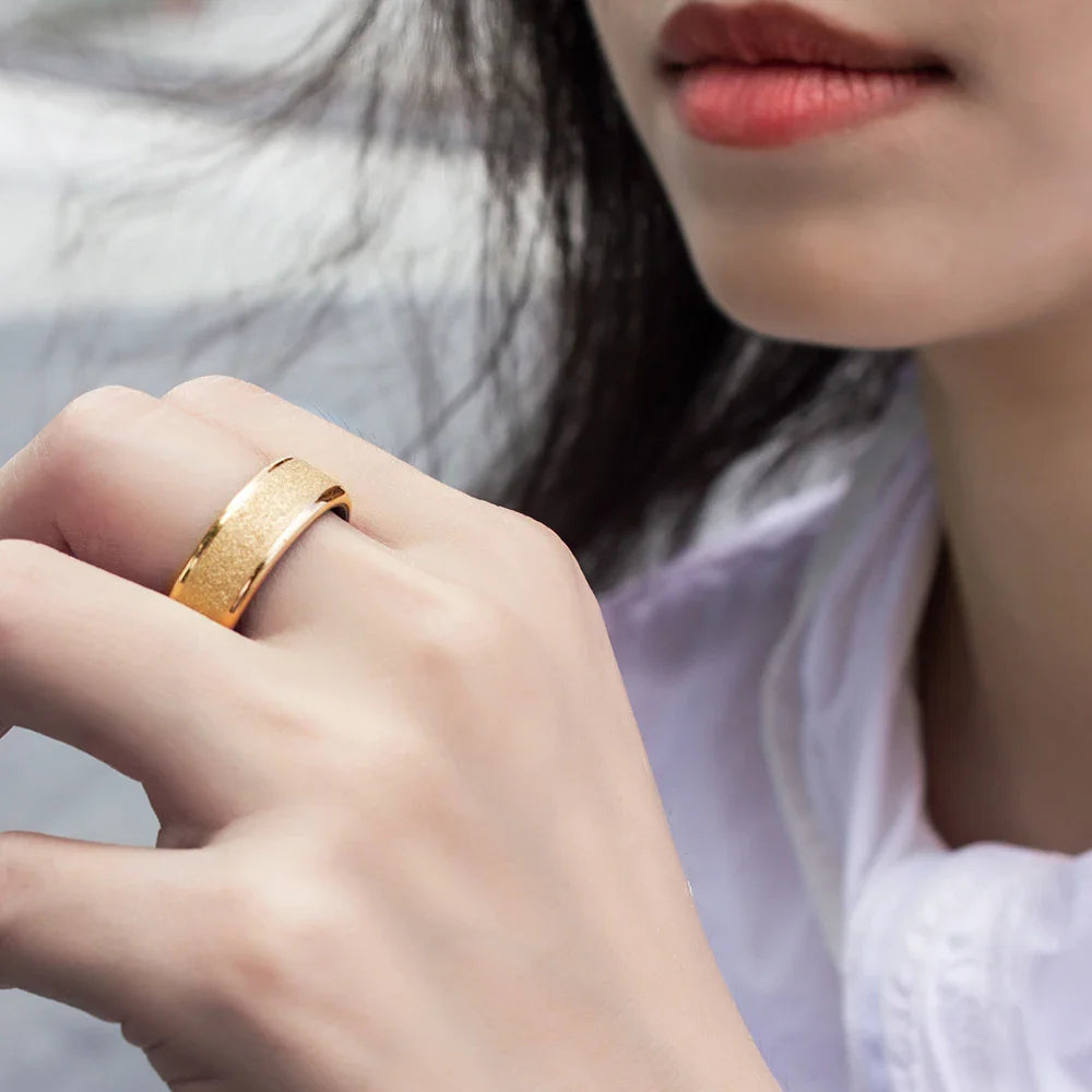 Close-up of a hand wearing a gold ring with a blurred background