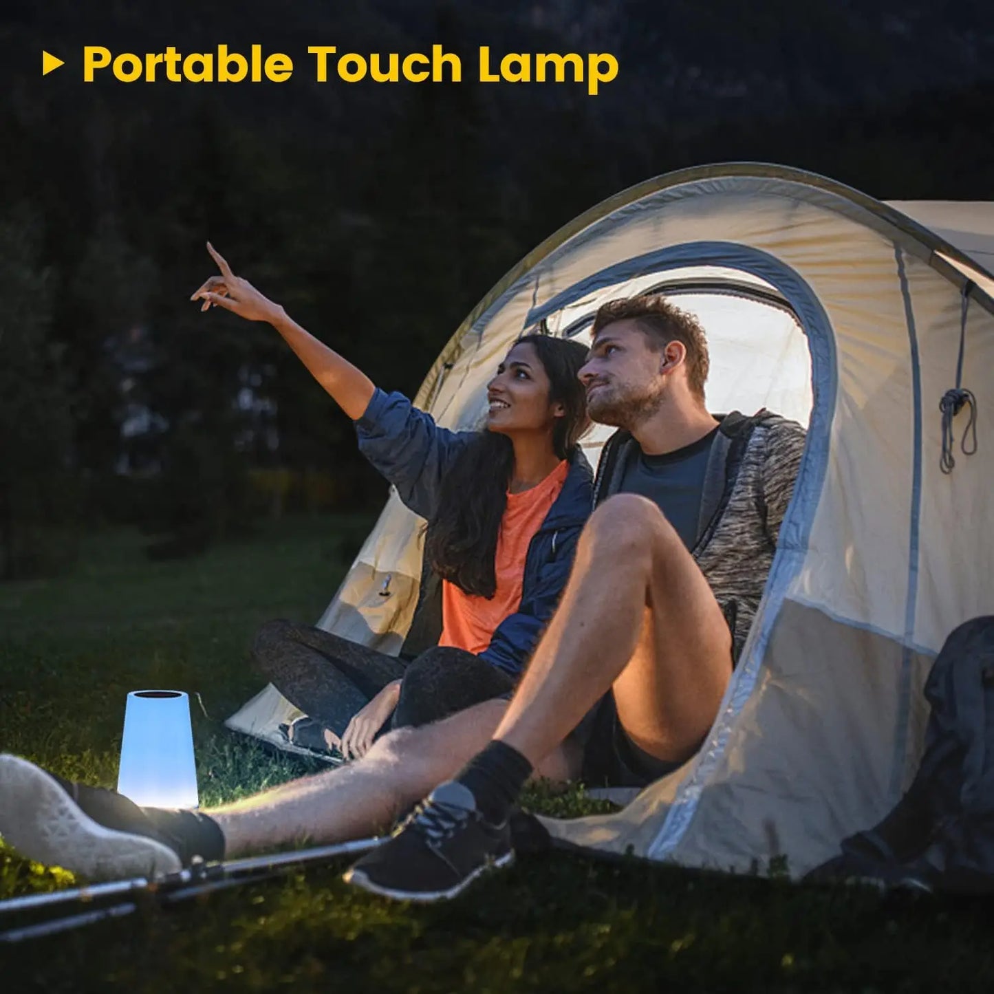 Couple camping with a portable touch lamp near their tent.