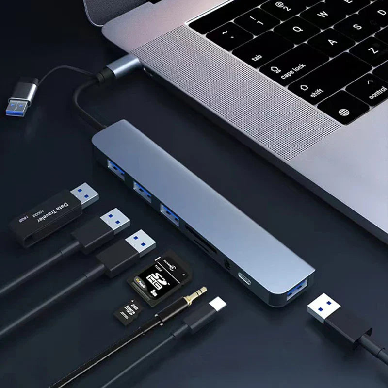 Laptop with USB hub and various USB devices on a dark surface