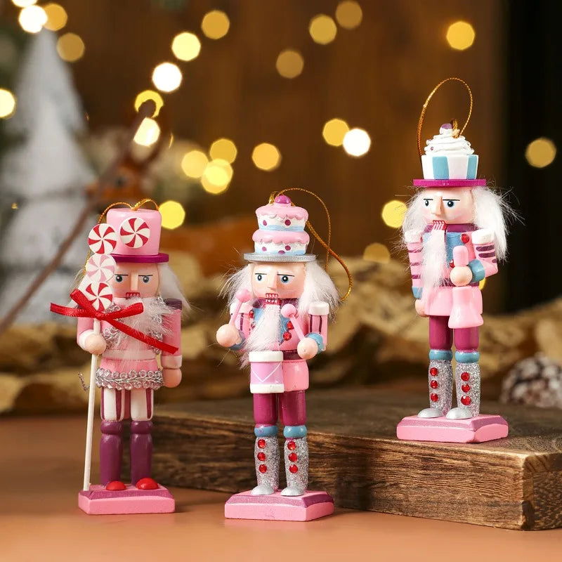 Three decorative nutcrackers in pink and white outfits with candy-themed accessories on a wooden surface.