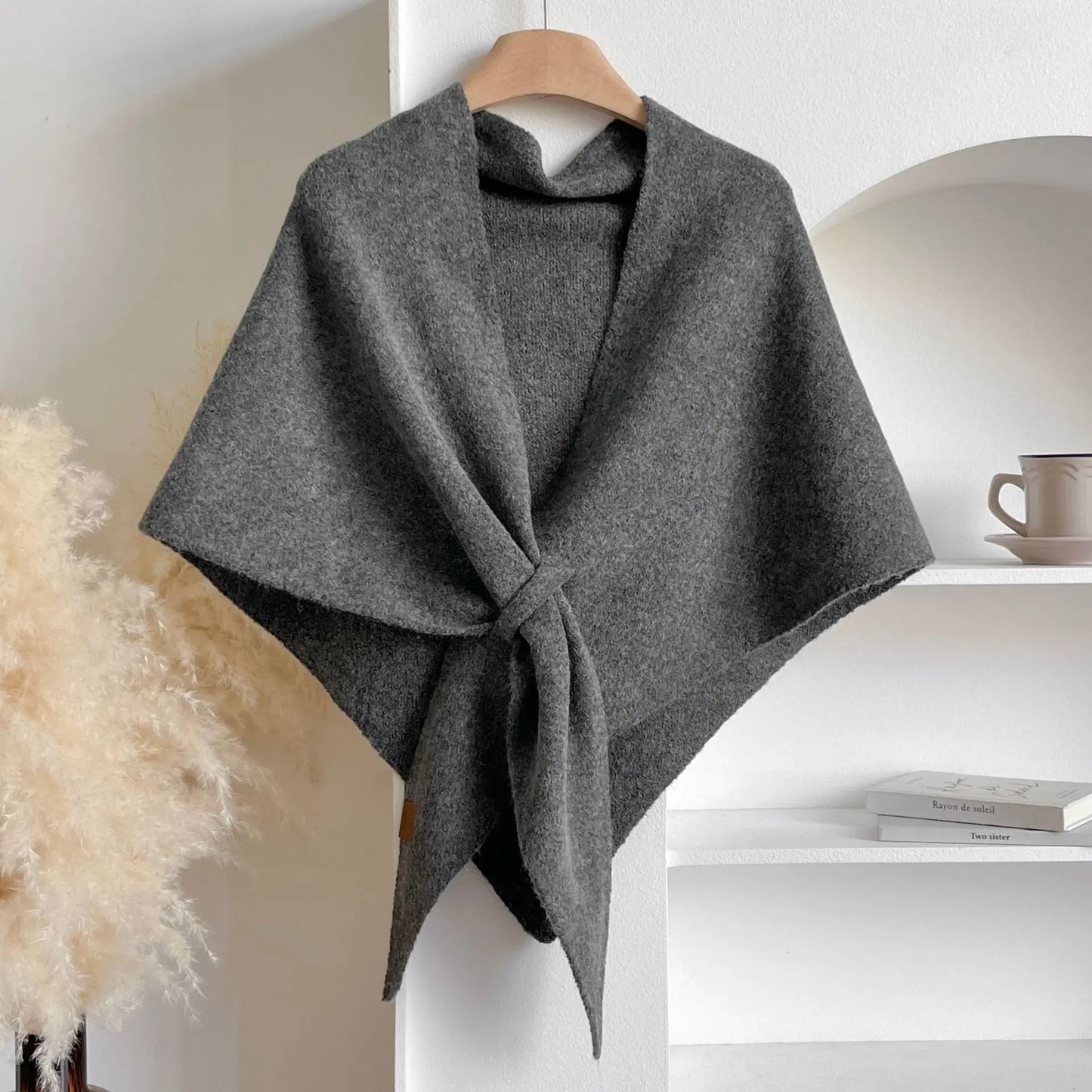 Gray poncho on a hanger against a neutral background