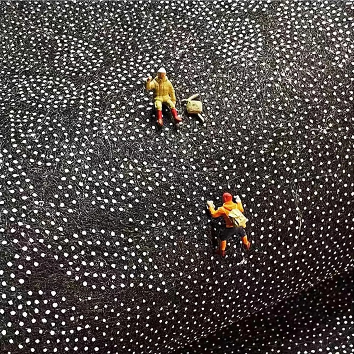 Two small figurines on a textured black and white surface