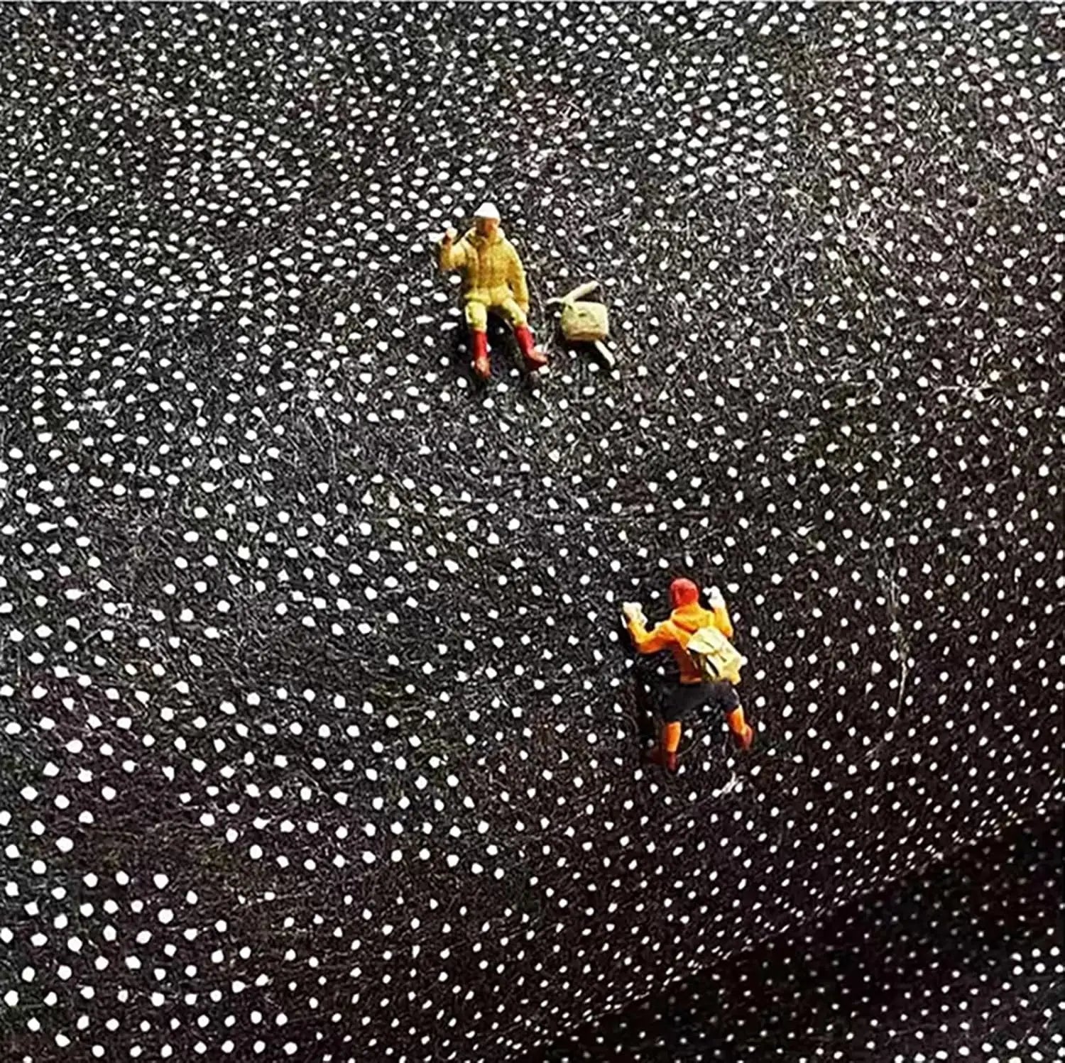 Two small figurines on a textured black and white surface