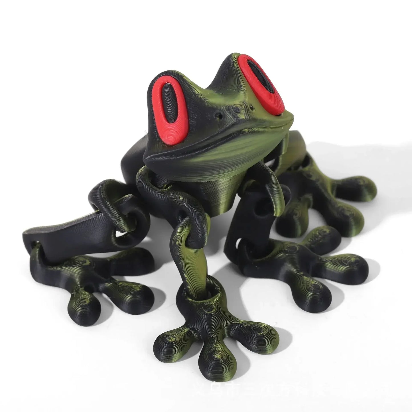 Green and black frog-shaped object with red eyes on a white background