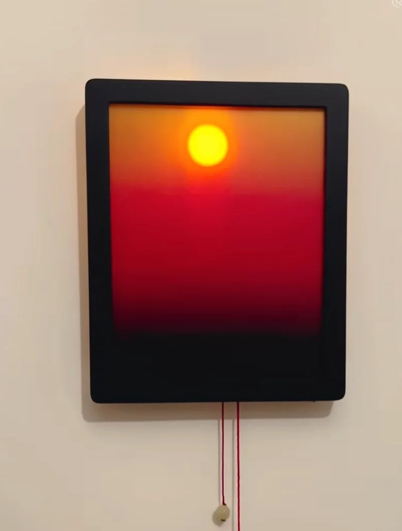 Sculpture of a sun with a black frame on a beige wall