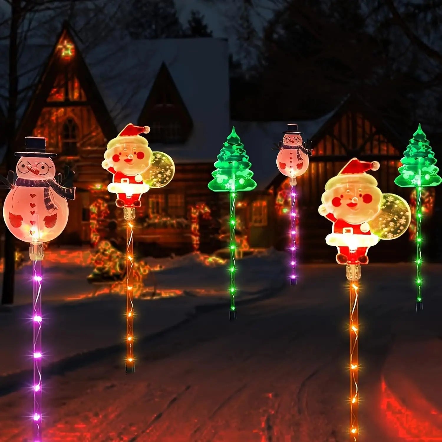 Decorative Christmas lights shaped like Santa Claus, snowmen, and trees on a snowy landscape.