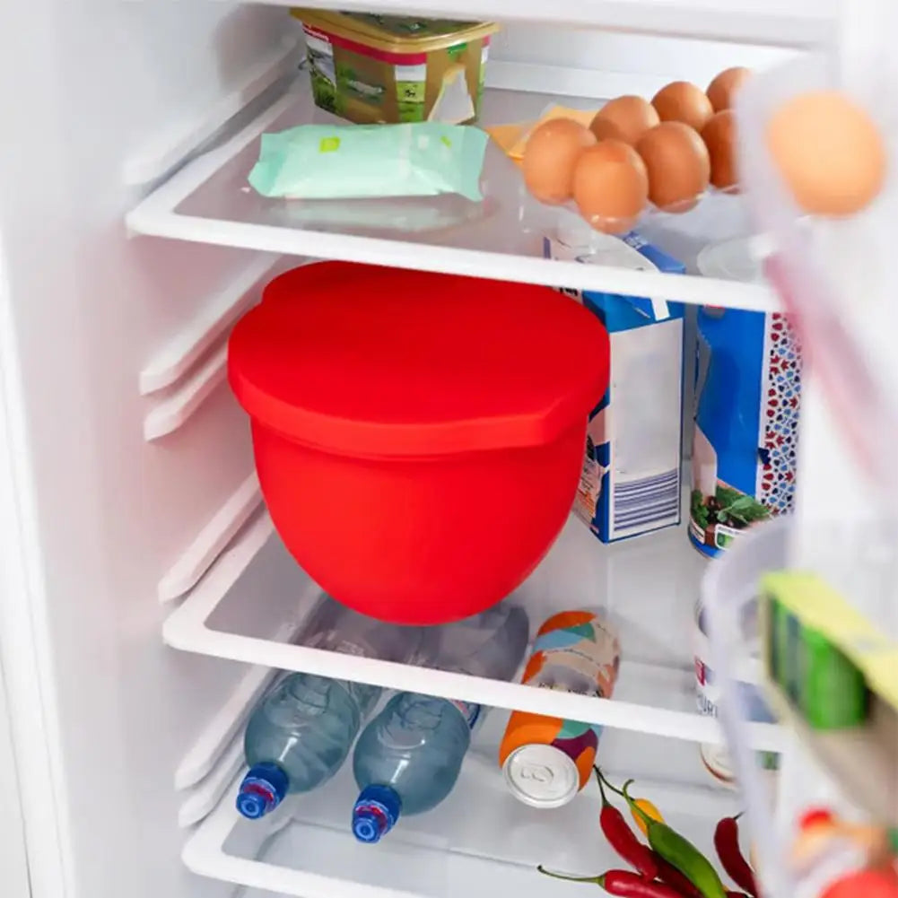 Red silicone lid on a container inside an open refrigerator with various items.