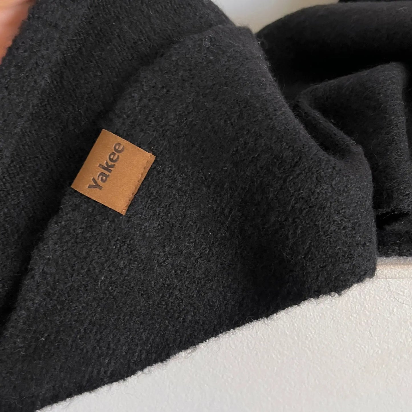 Black fleece blanket with a brown label on a white surface