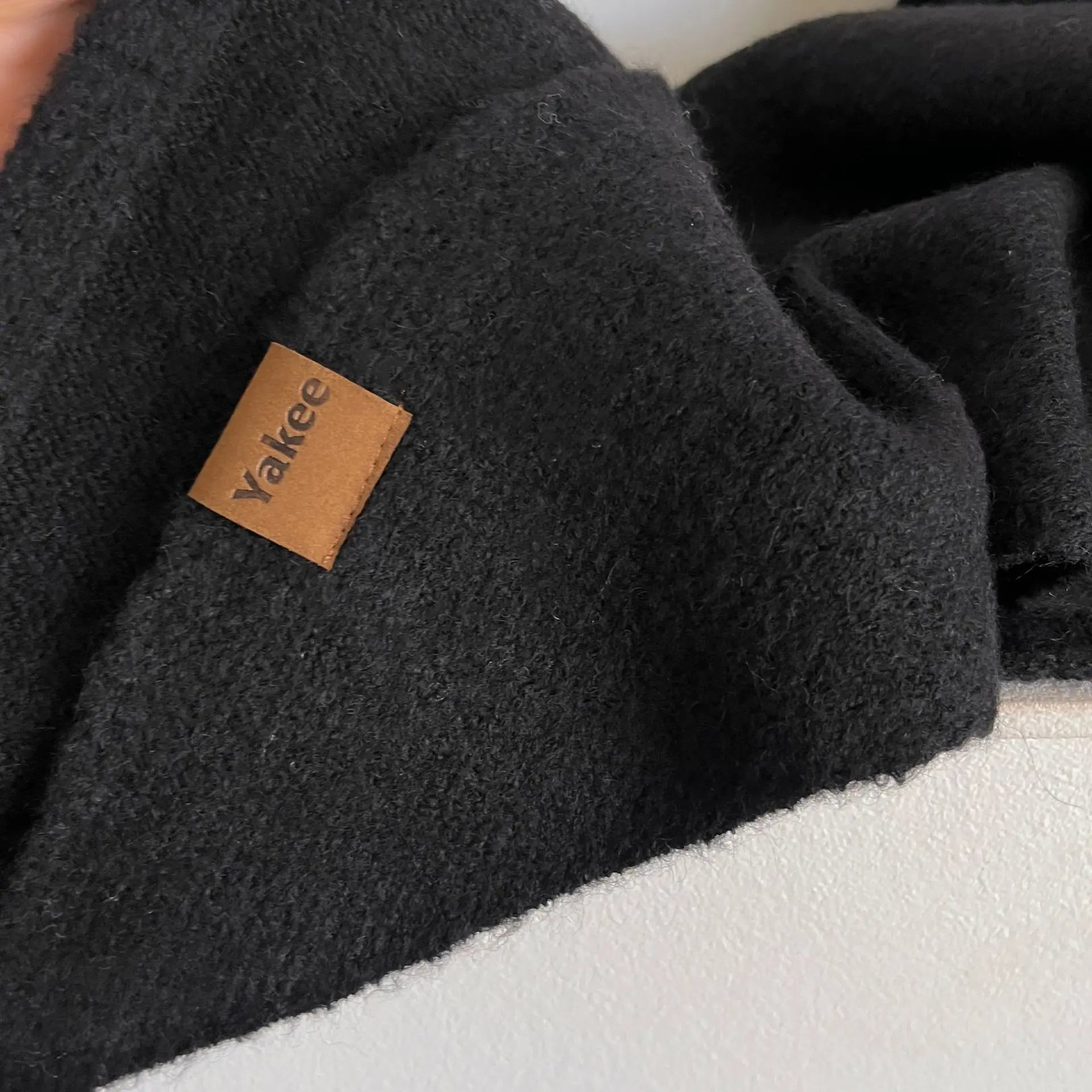 Black fleece blanket with a brown label on a white surface