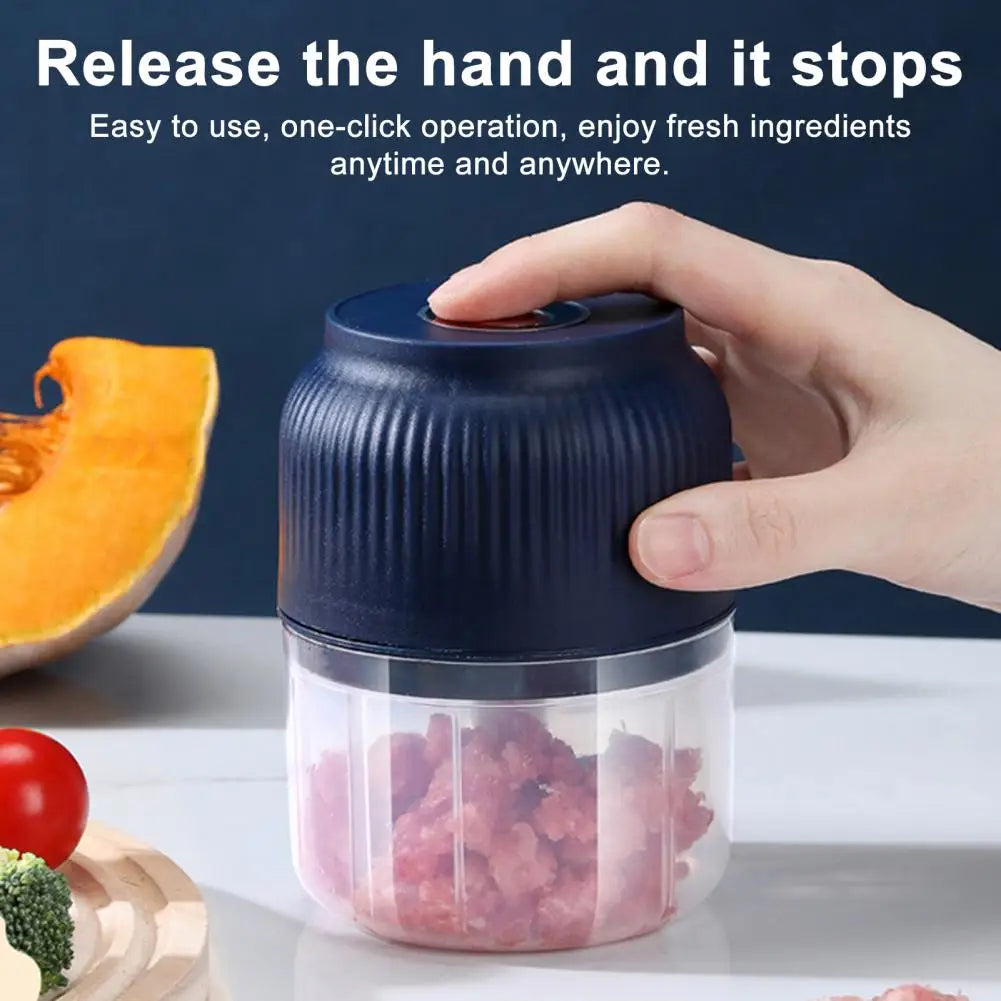 Hand holding a blue food chopper with chopped ingredients, surrounded by vegetables on a dark background.
