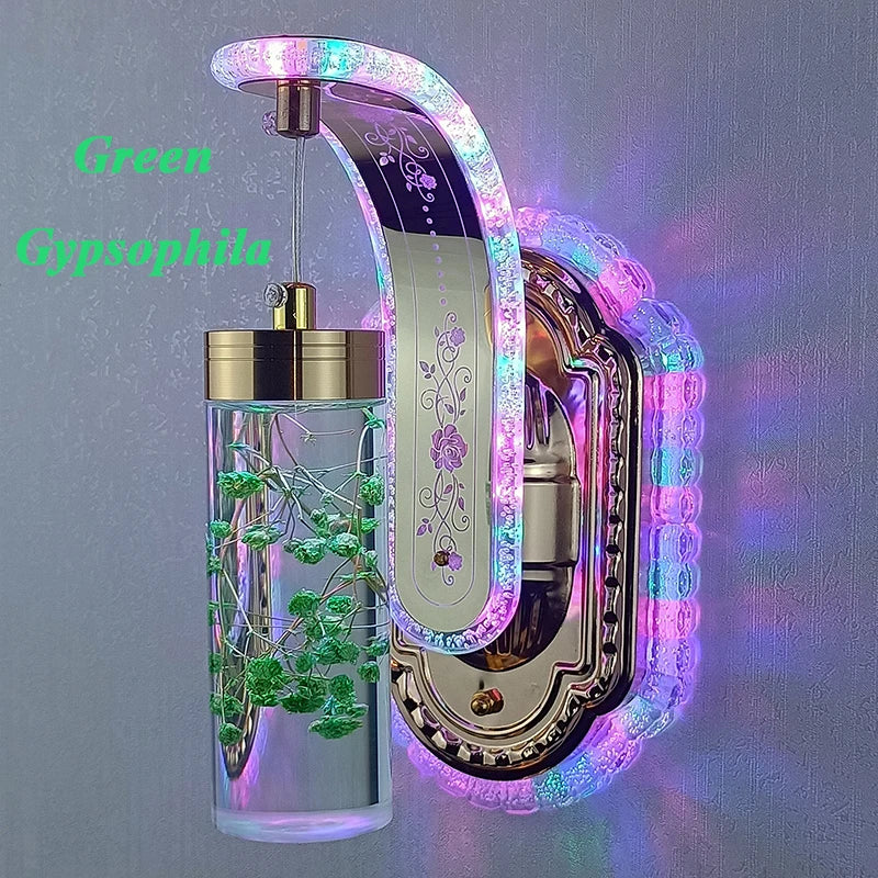 Decorative wall light with a glass container holding green gypsothila on a gray background.