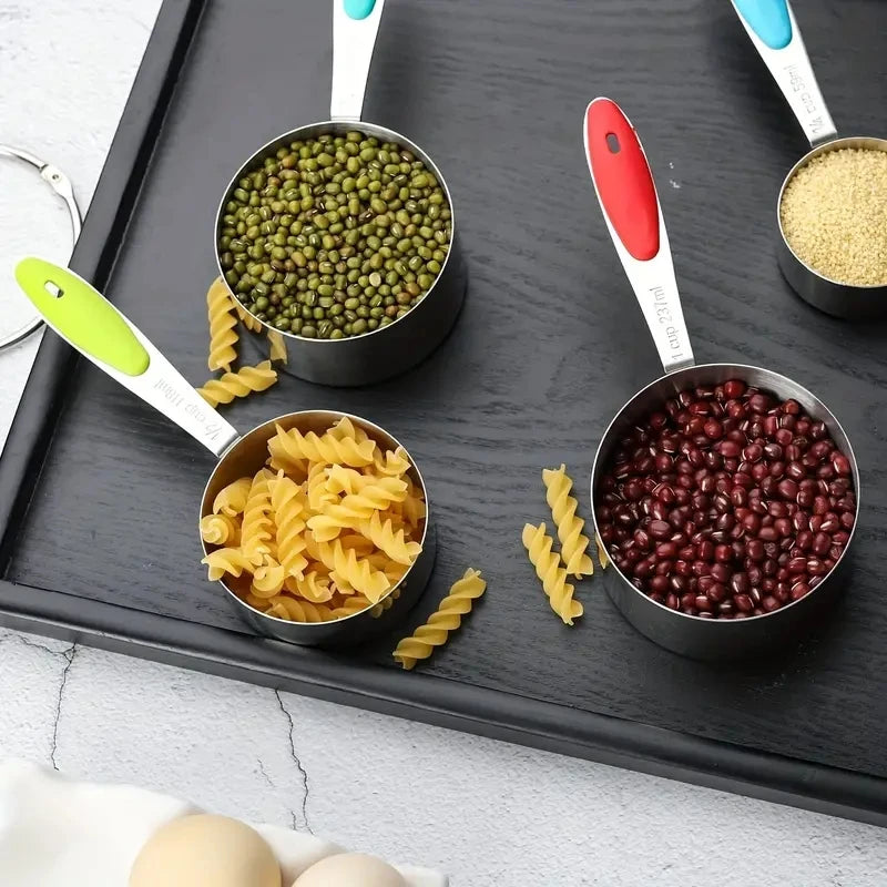 Measuring cups with various dry foods on a black tray