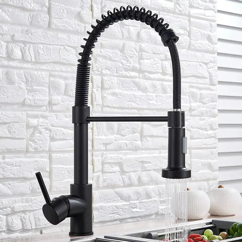 Black kitchen faucet with a flexible hose against a white brick wall.
