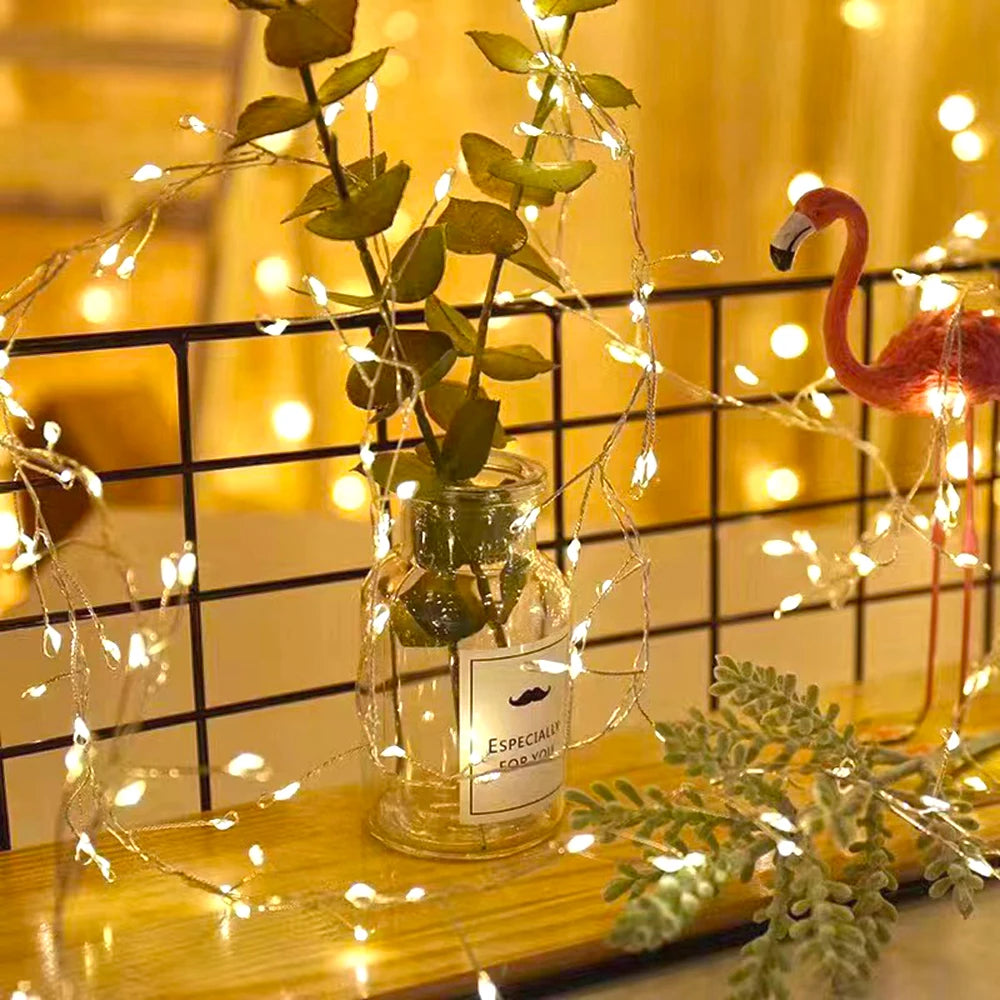 Decorative string lights with a plant and flamingo figurine on a shelf.