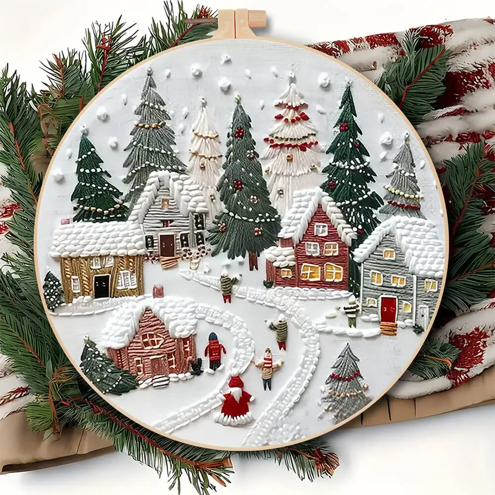 Decorative embroidery hoop with a winter village scene surrounded by Christmas trees.